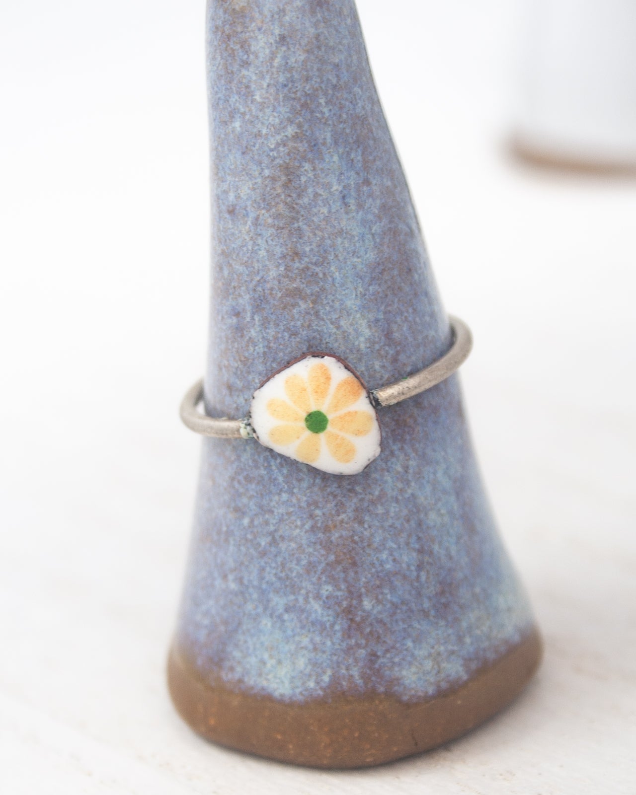 A ring with a flower design on it, placed on a blue ceramic stand.