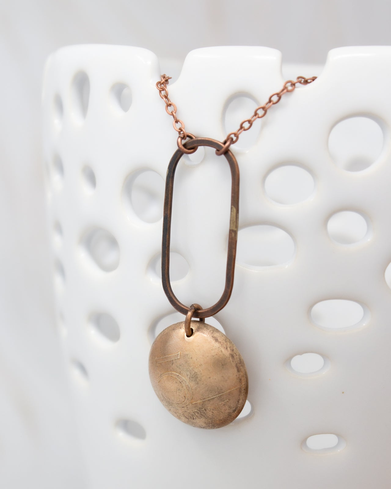 A necklace with a circular pendant hanging from a metal frame, displayed against a white background.