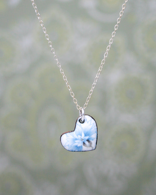 a heart shaped necklace with a blue flower on it