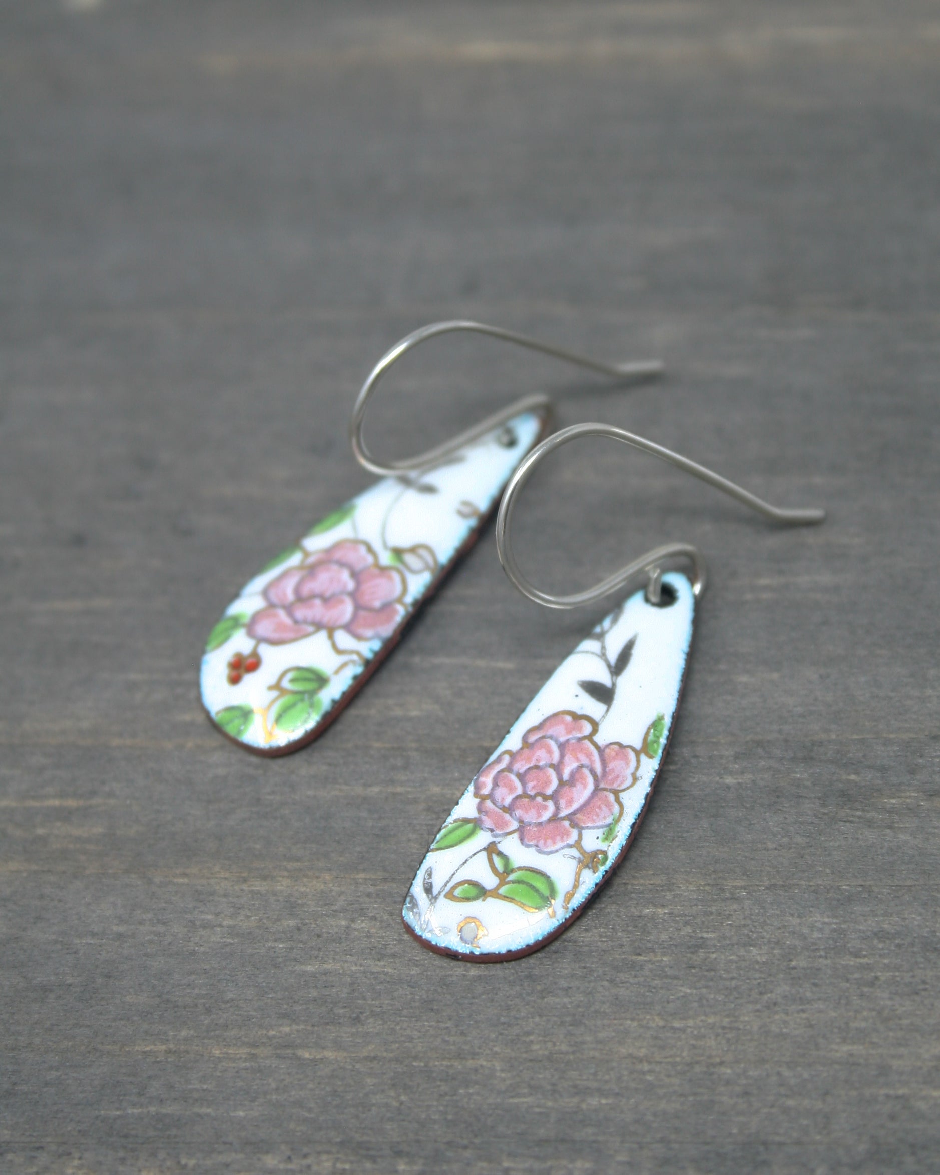 a pair of earrings with flowers painted on them