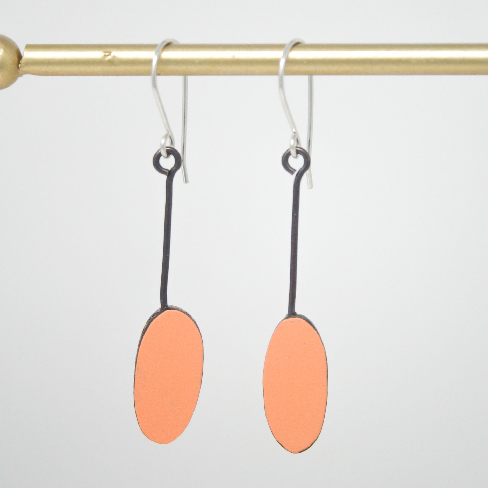 a pair of earrings hanging from a metal bar