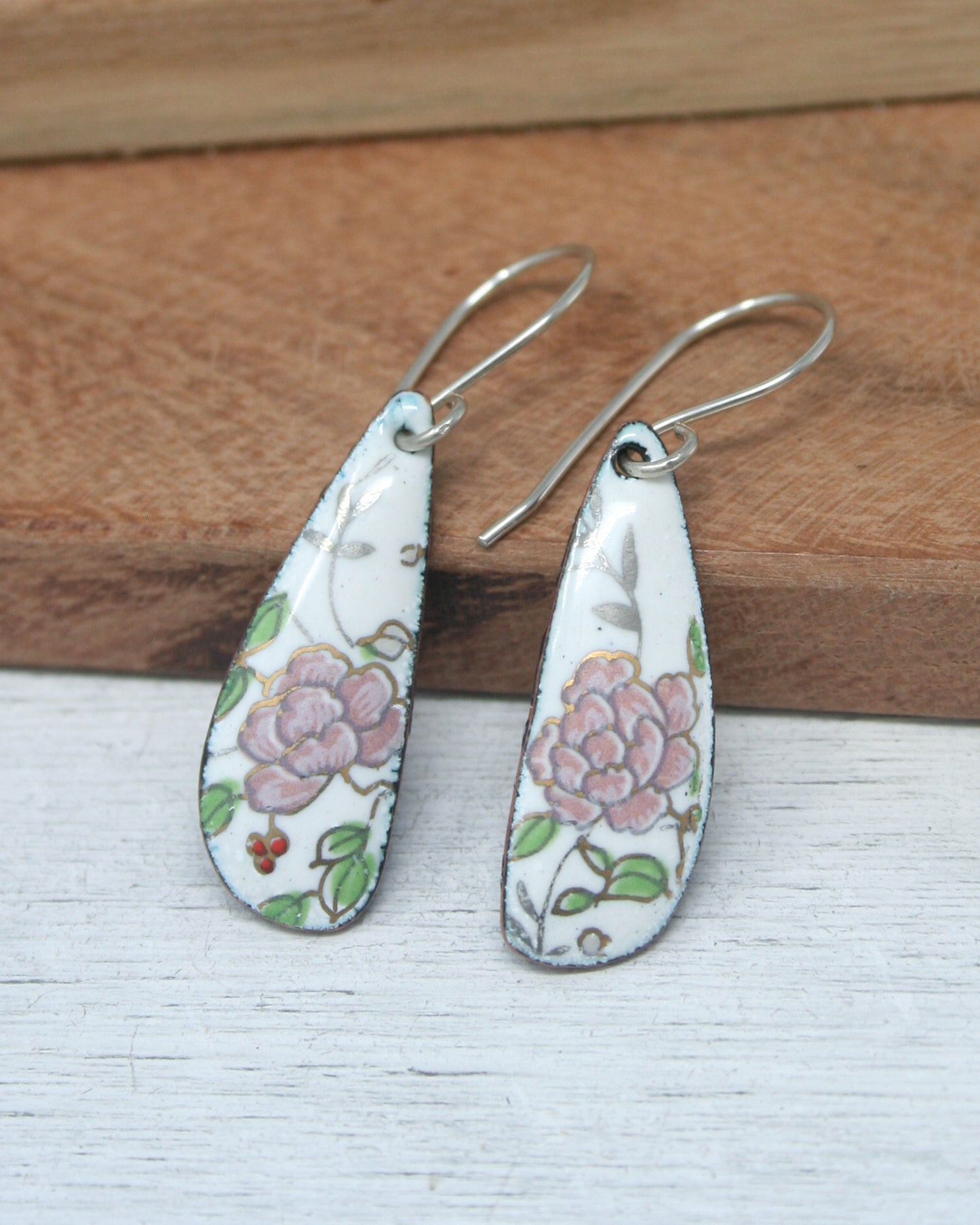 a pair of earrings with flowers painted on them