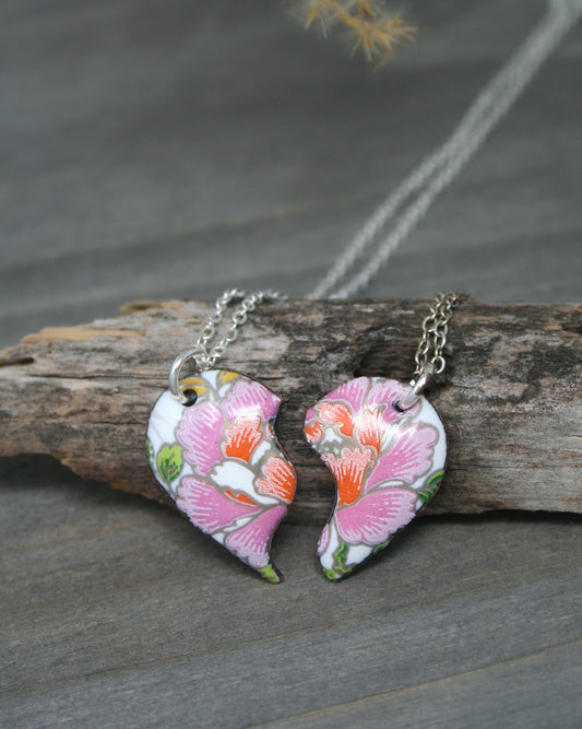 two pink flowers are hanging from a silver chain