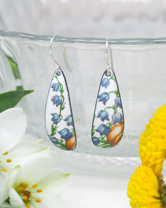 a close up of a pair of earrings near a flower