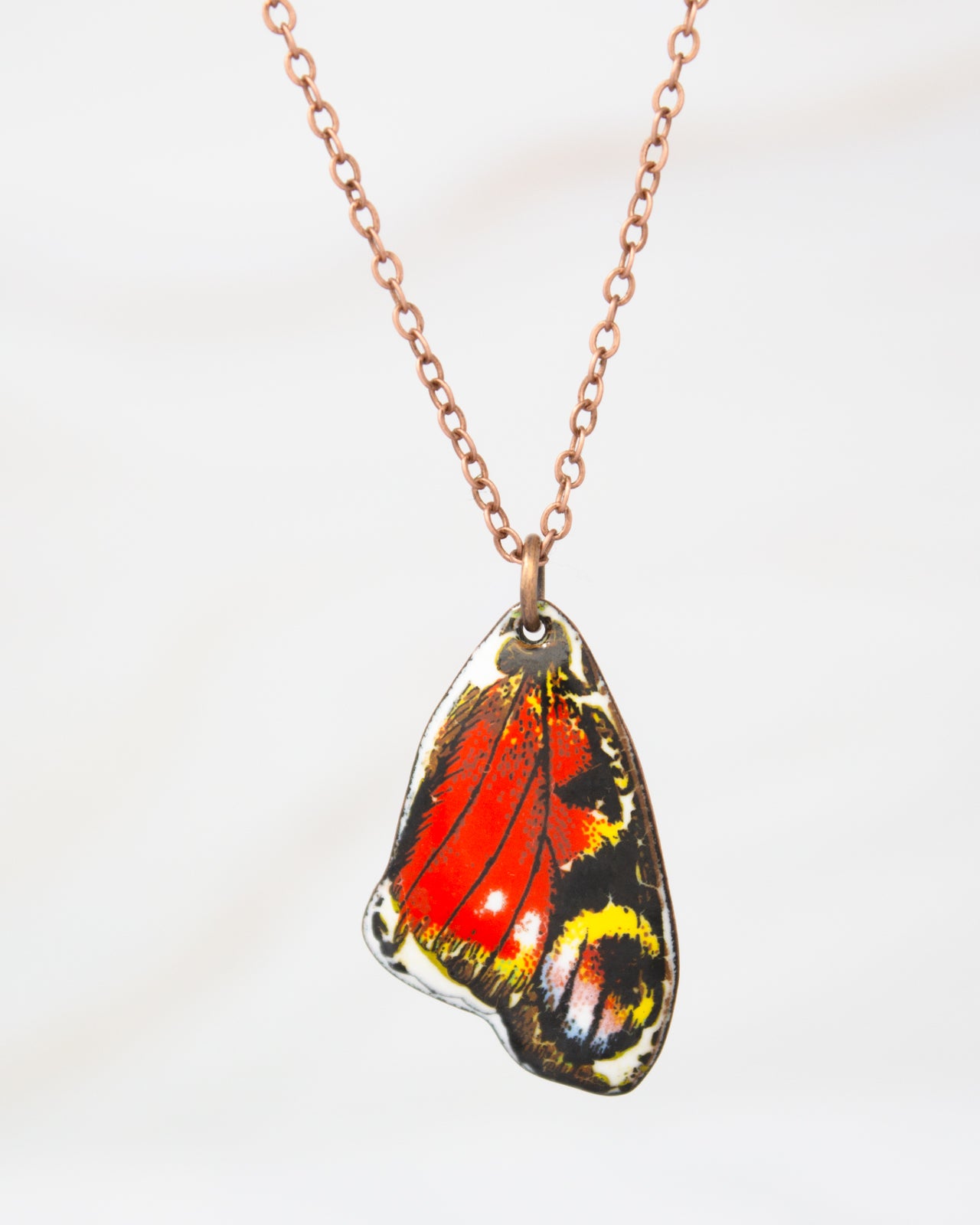 A necklace with a pendant featuring a colorful butterfly wing design.
