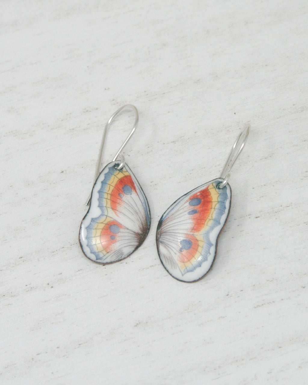 a pair of butterfly shaped earrings sitting on top of a table