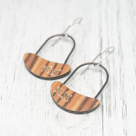 a pair of earrings with a wooden design on them