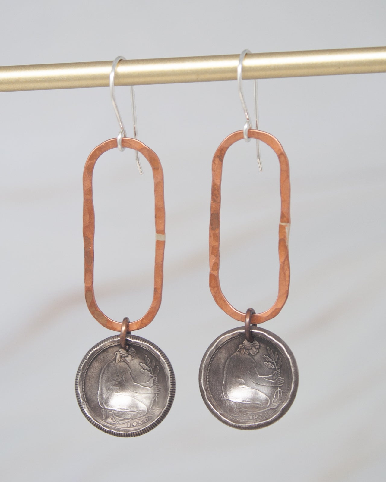 A pair of earrings with a metal frame and a metal pendant featuring a design.