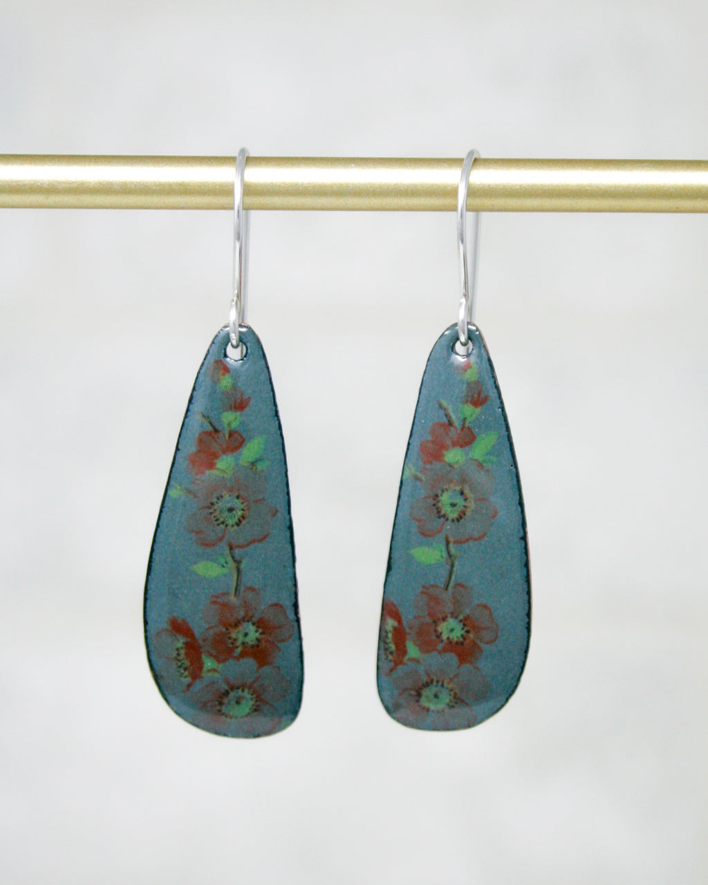 A pair of earrings with a floral design on a gold-colored metal bar.