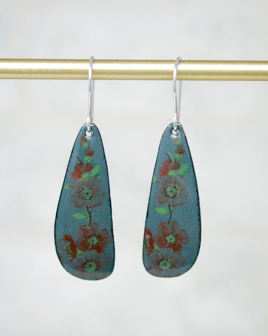 A pair of earrings with a floral design on a gold-colored metal bar.