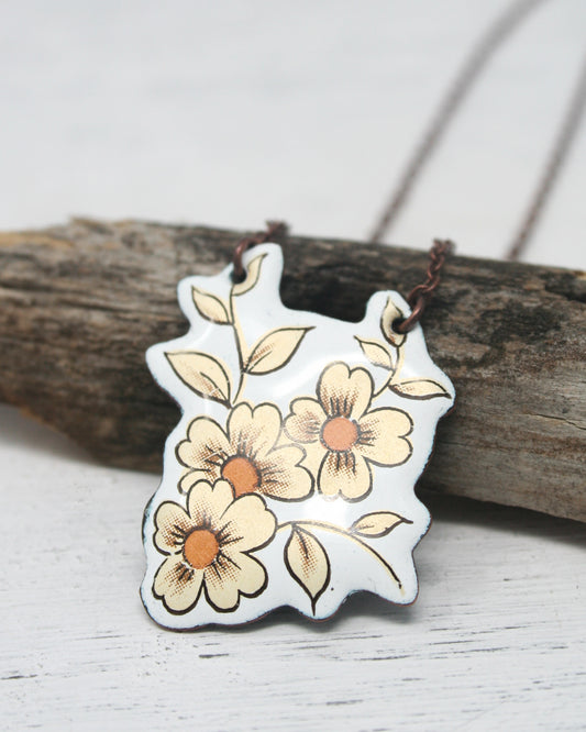 a white and yellow flower pendant on a brown cord