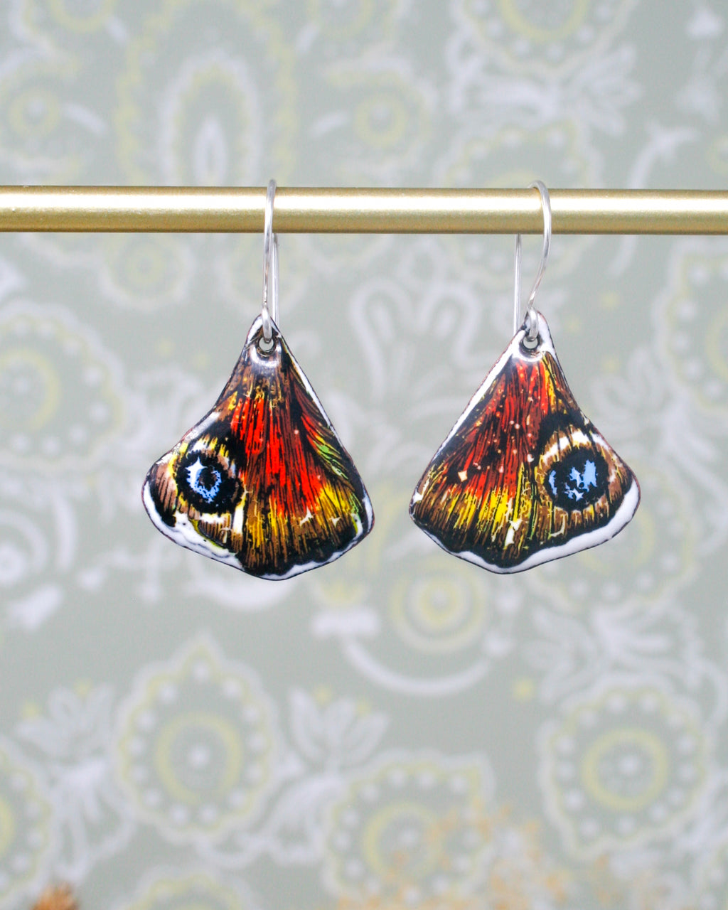 a pair of butterfly shaped earrings hanging from a clothes line