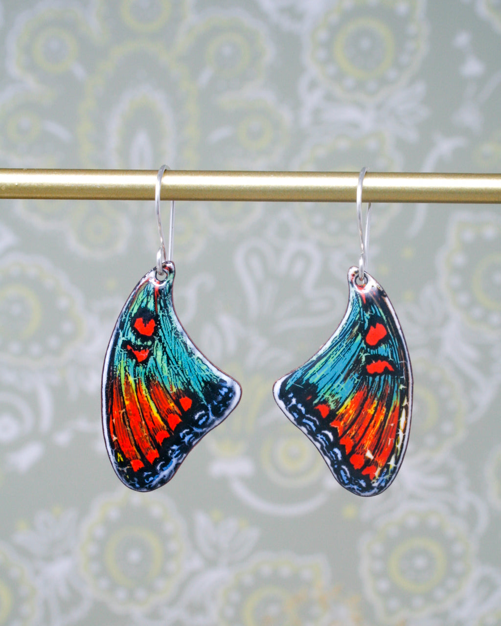 a pair of colorful butterfly shaped earrings hanging from a hook