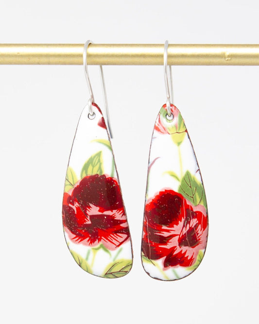 A pair of earrings with a floral design, featuring red and green flowers against a white background.