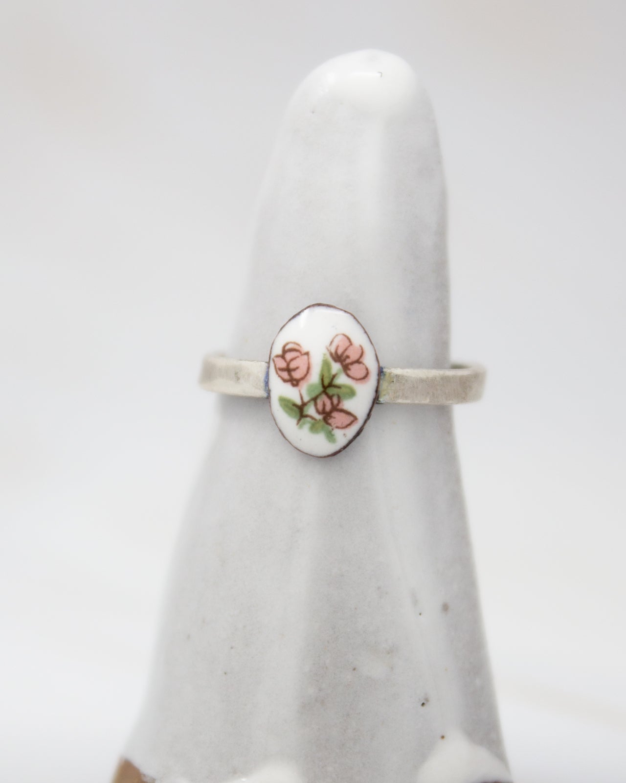 A white ceramic ring with a floral design on it, placed on a white surface.