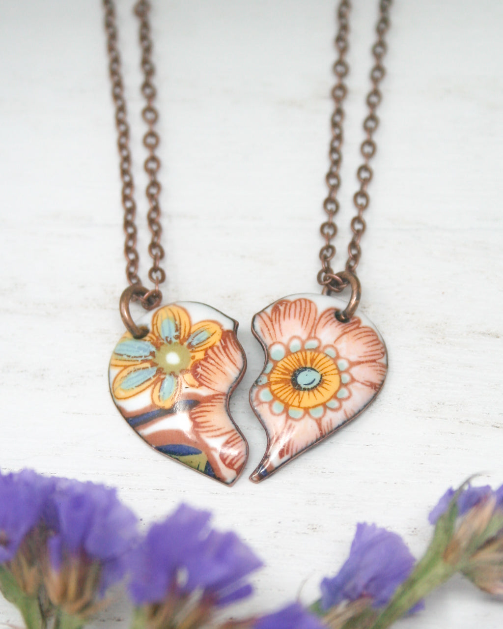 a couple of heart shaped pendants sitting on top of a purple flower