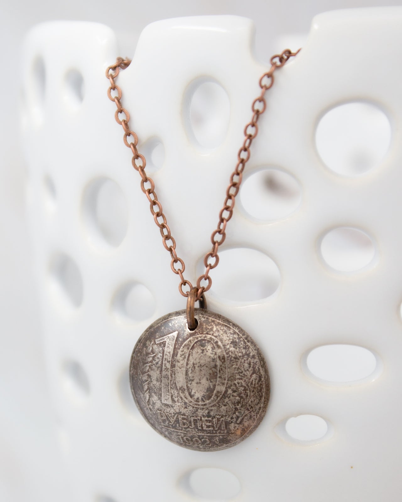 A necklace with a pendant featuring the number 10, possibly a coin, hanging from a chain.