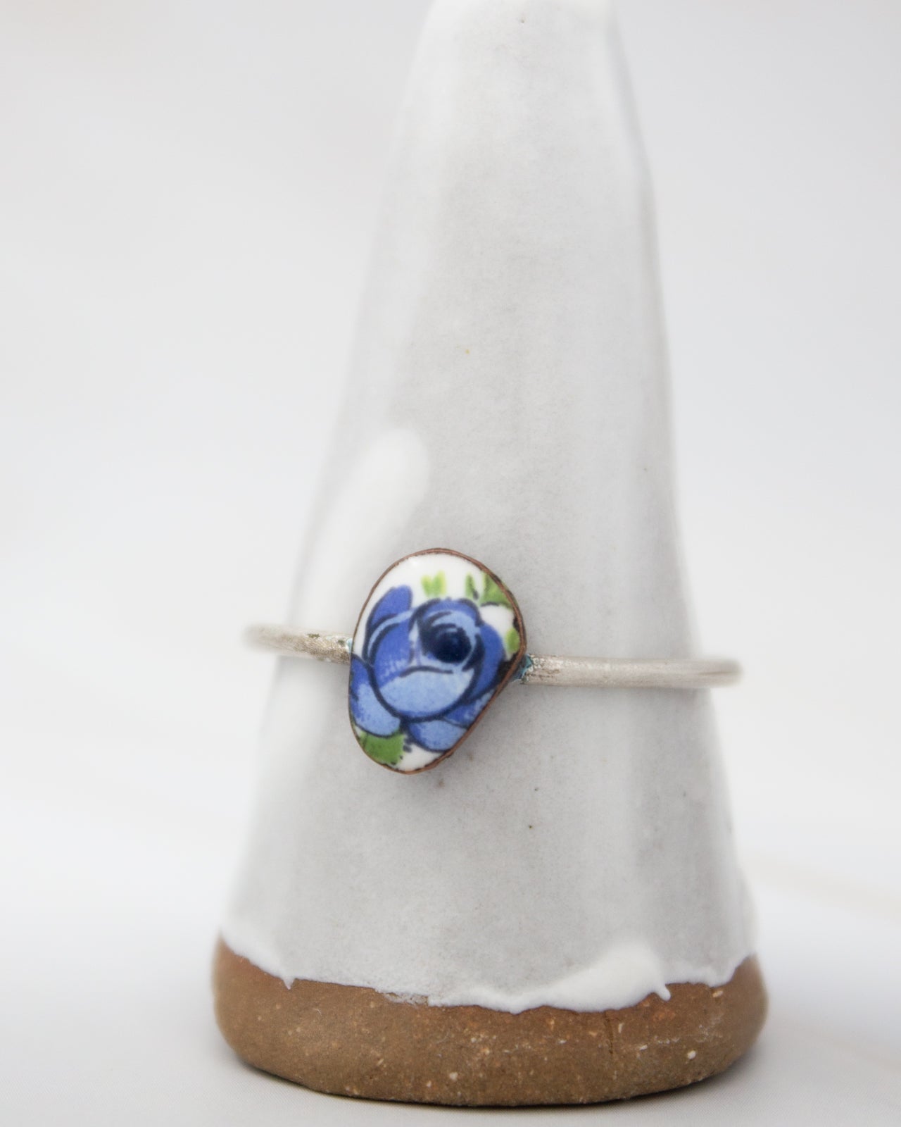 A white ceramic ring stand with a blue floral design on it.