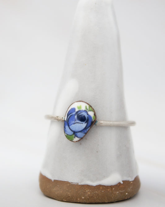 A white ceramic ring stand with a blue floral design on it.