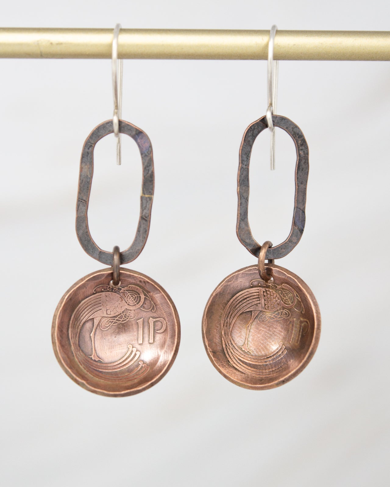 A pair of copper-colored earrings with a circular design on the front and a larger circular design on the back.