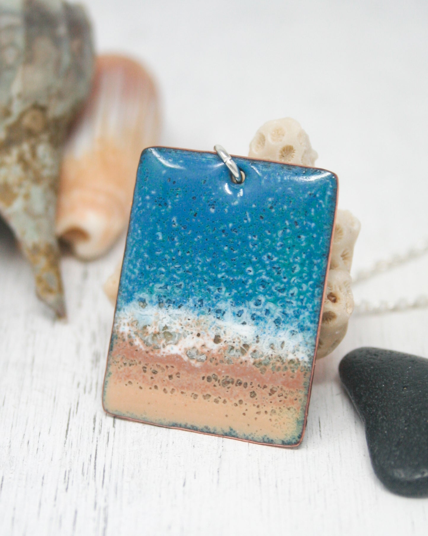 a necklace with a blue, orange and white square pendant