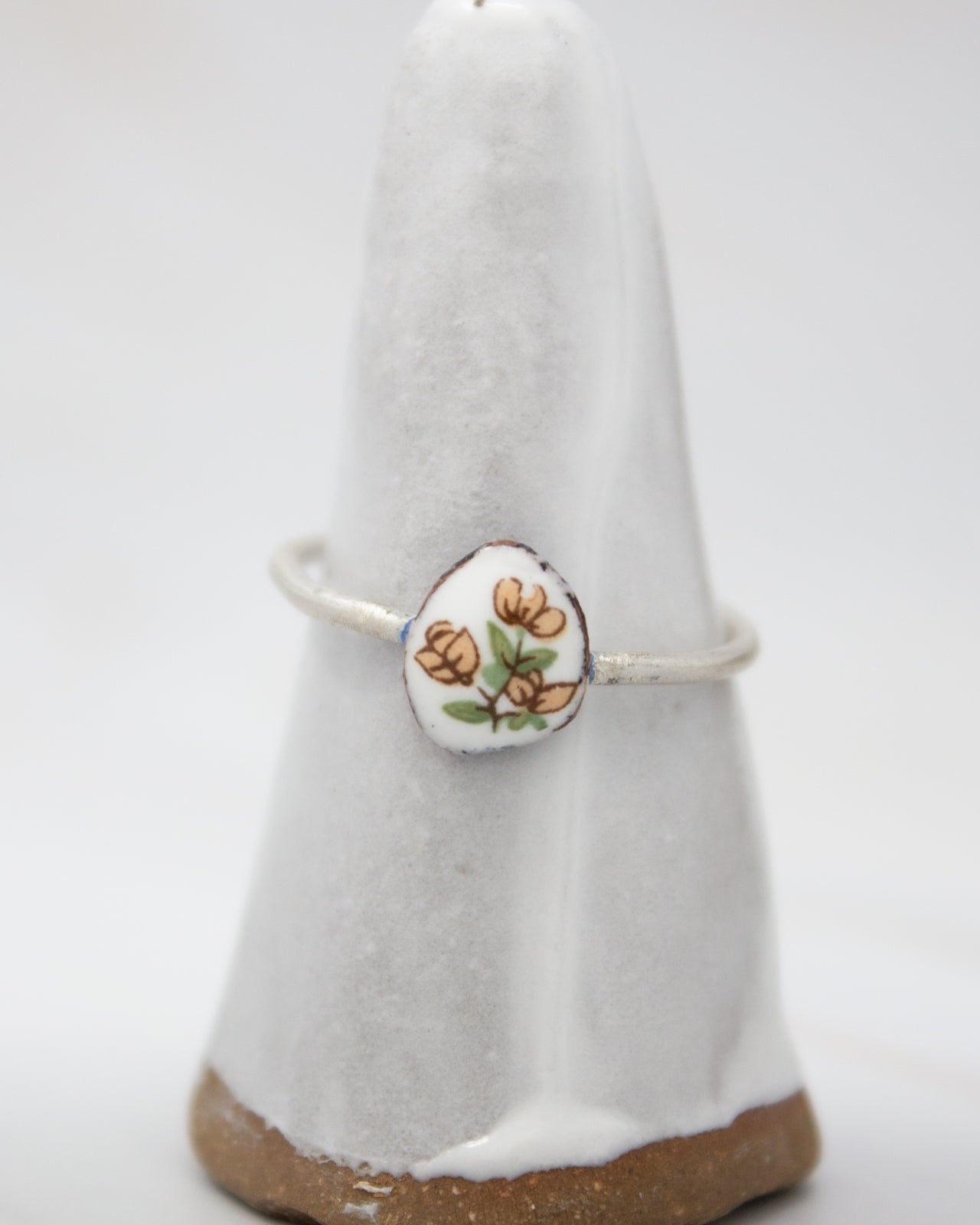 A white ceramic ring stand with a floral design on it.