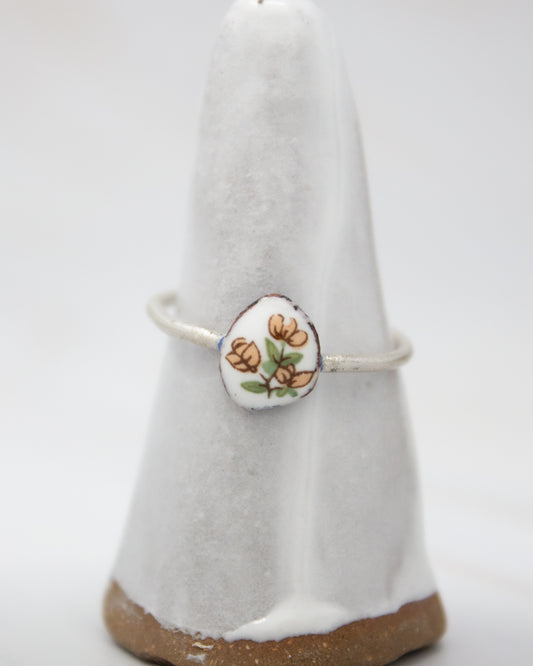 A white ceramic ring stand with a floral design on it.