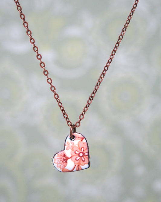 a necklace with a heart and flowers on it