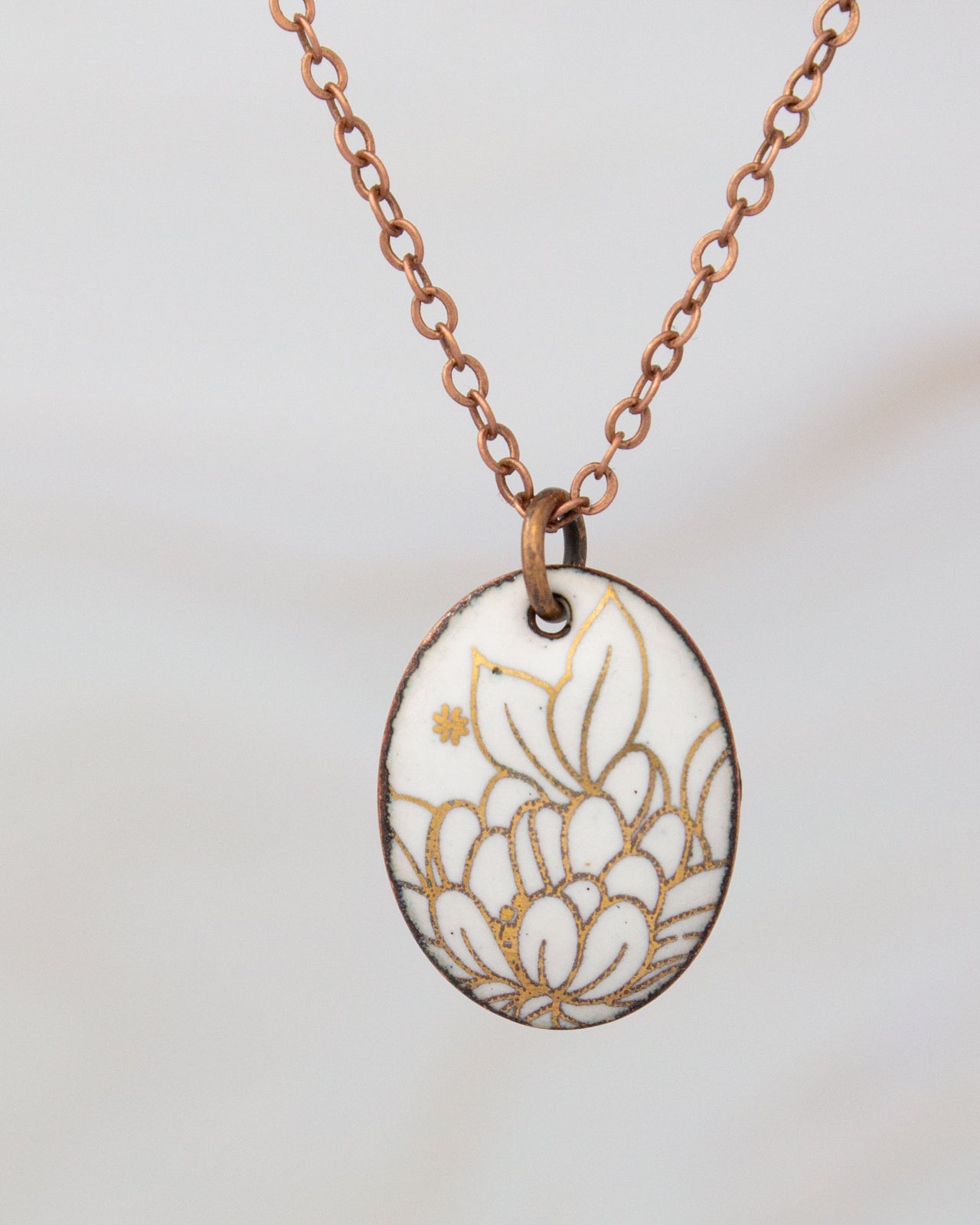 A necklace with a pendant featuring a floral design in white and gold colors.