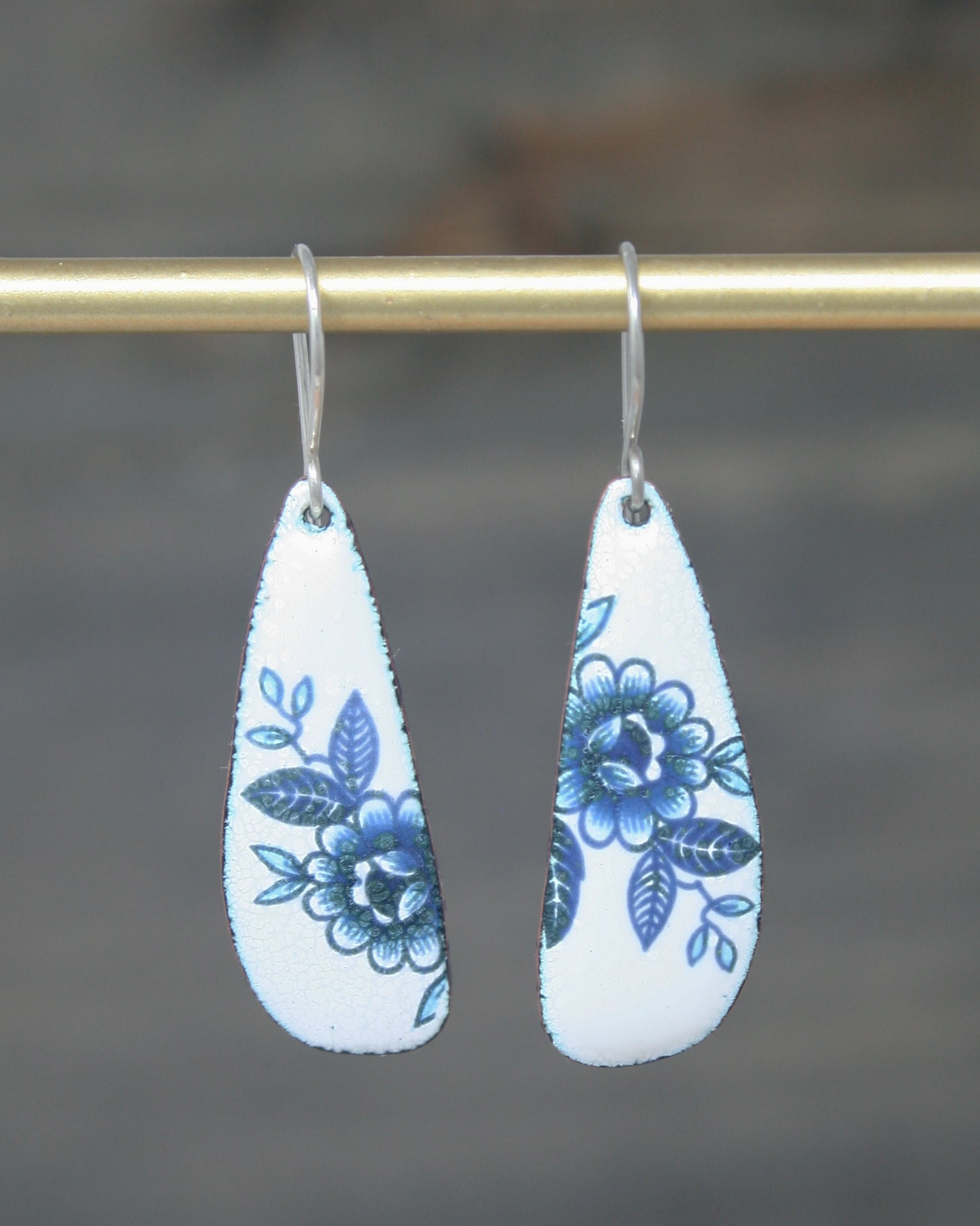 a pair of blue and white earrings hanging from a hook