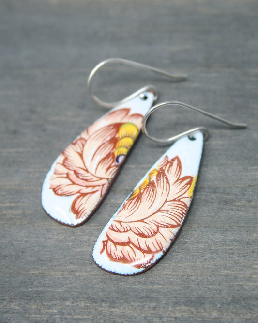 a pair of earrings with flowers painted on them