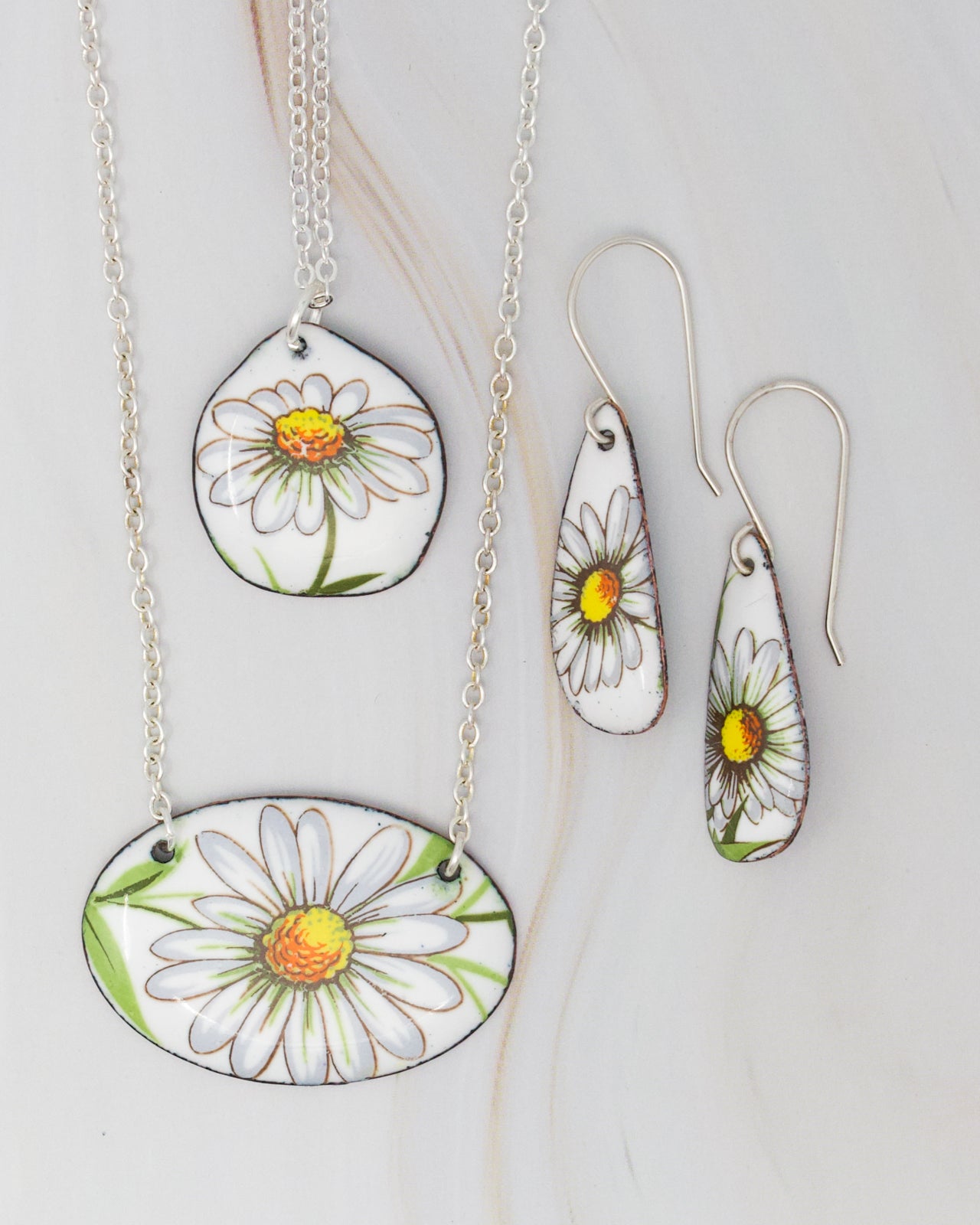 a collection of jewelry featuring white and yellow flowers, including earrings and a necklace.