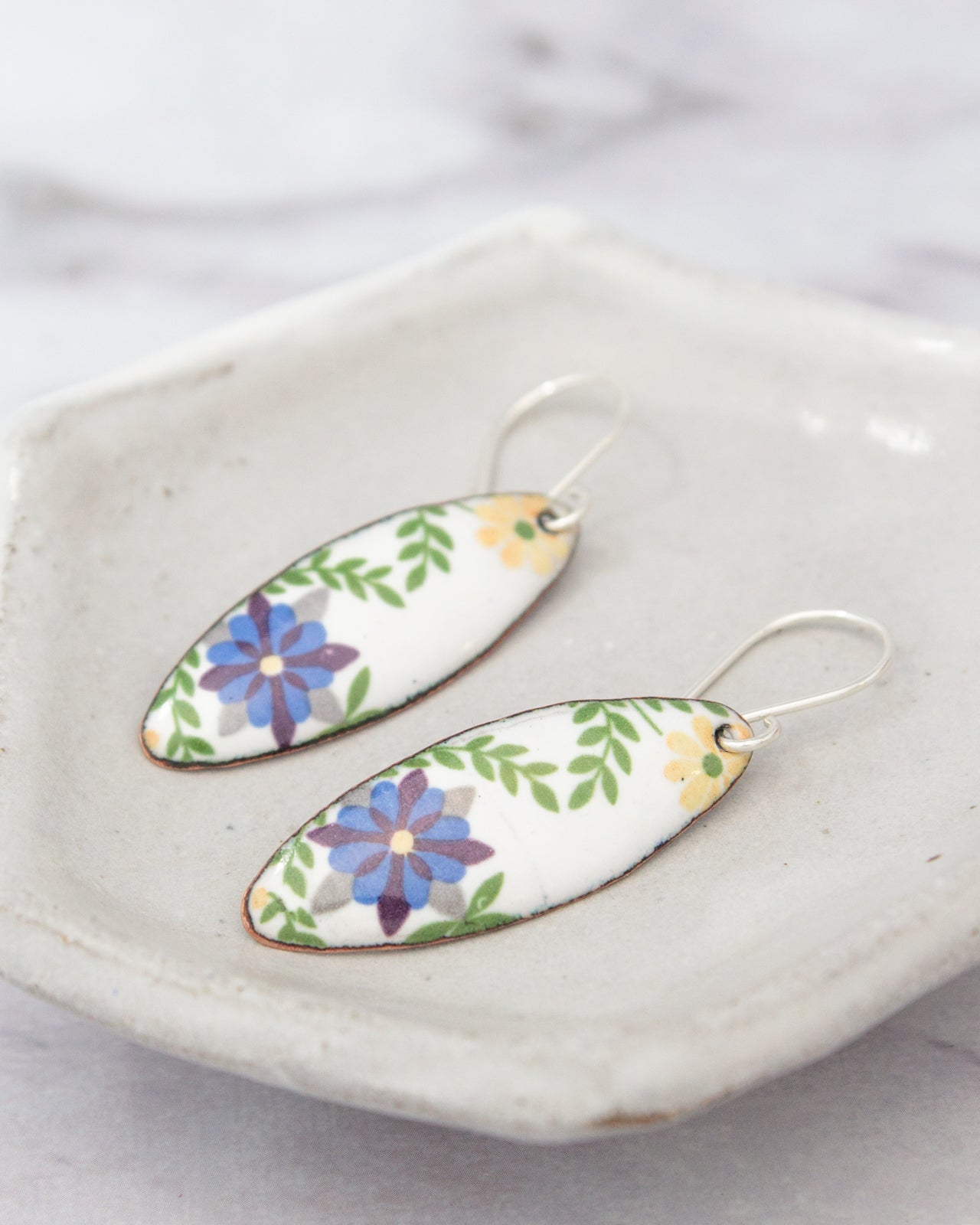 A pair of earrings with a floral design on a white plate.