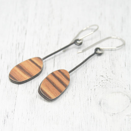 a pair of wooden earrings sitting on top of a white table