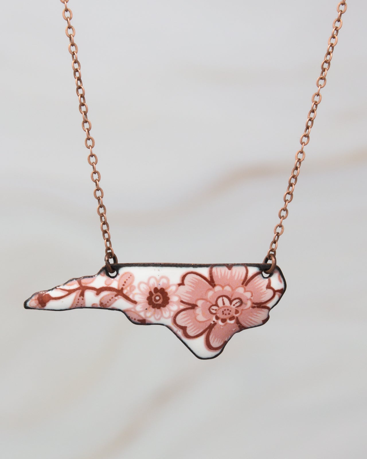 A necklace with a pendant in the shape of the state of North Carolina.