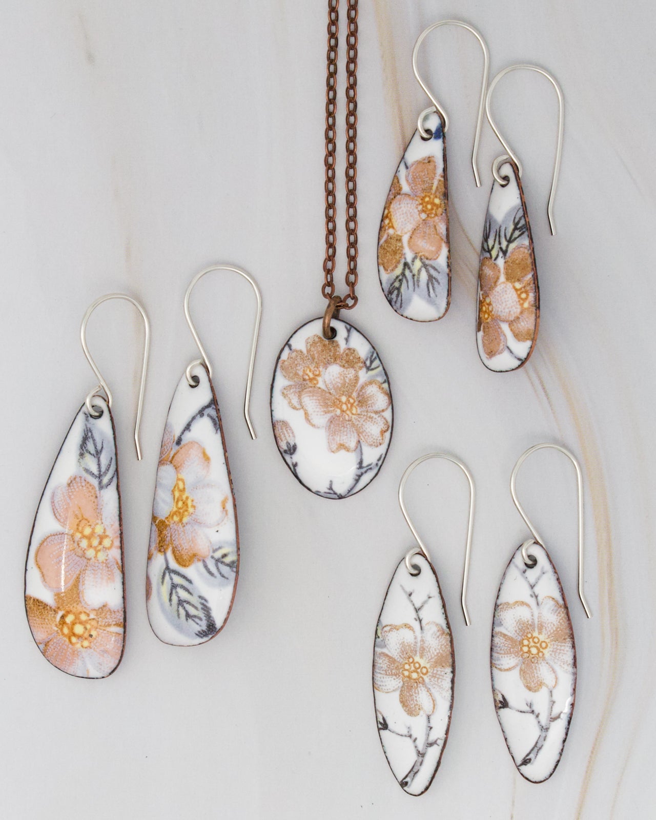 a collection of earrings and a necklace featuring floral designs in shades of white and orange.
