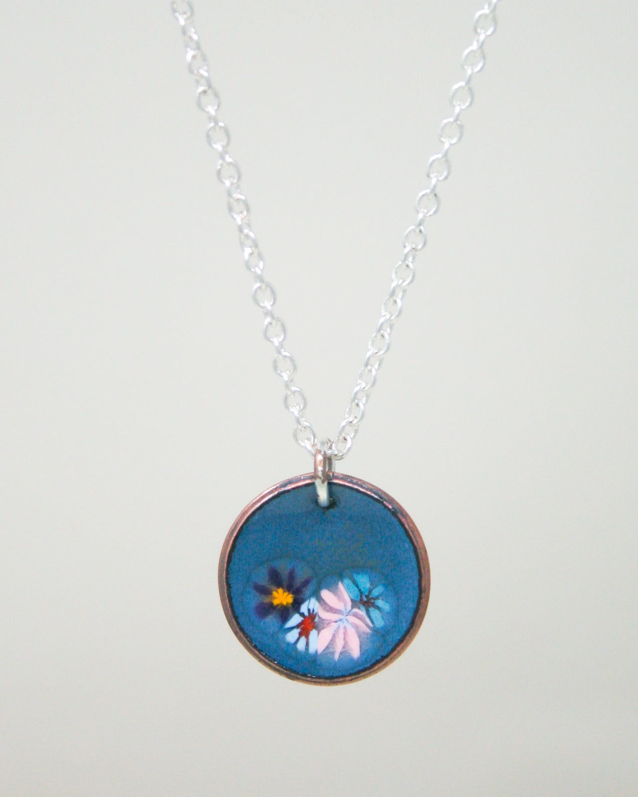A necklace with a blue pendant featuring a floral design.