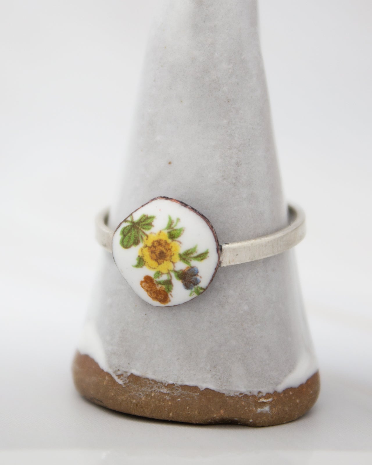 A white ceramic ring stand with a floral design on it.
