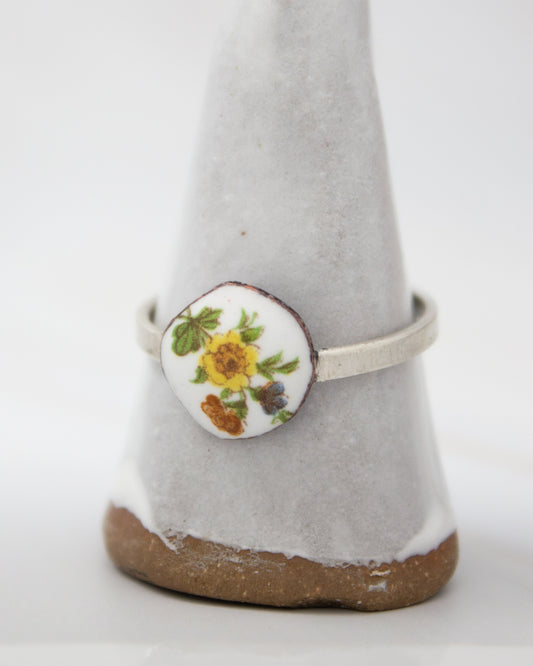 A white ceramic ring stand with a floral design on it.