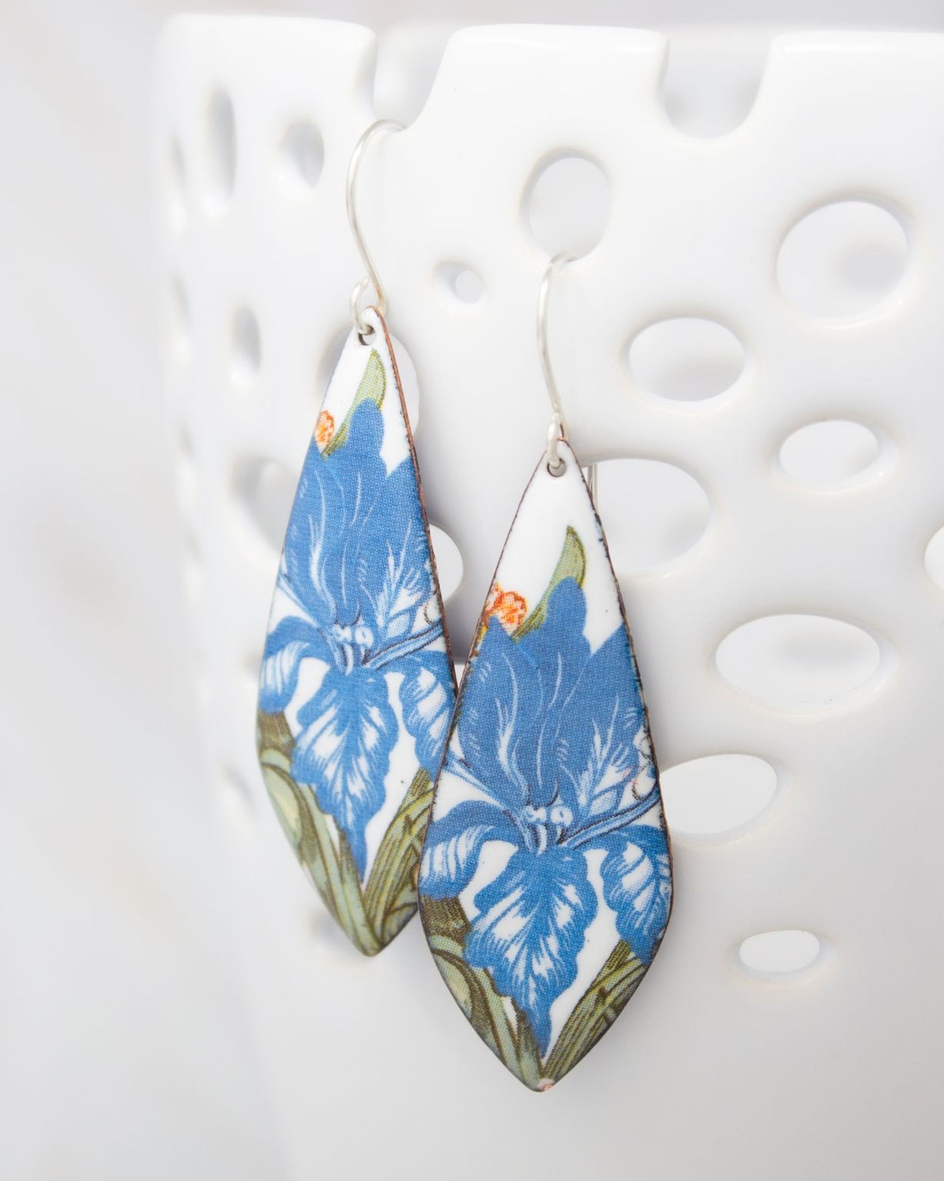 A pair of earrings with blue floral designs on a white background.