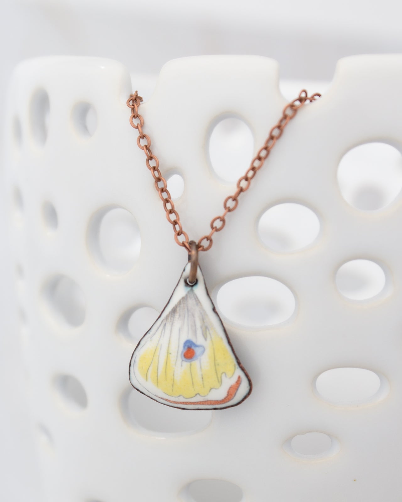 A necklace with a pendant in the shape of a seashell, featuring a colorful design.