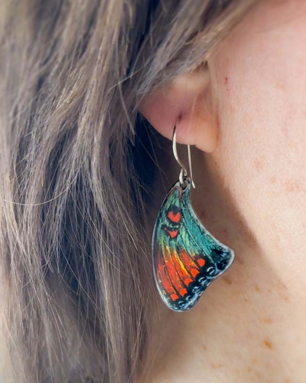 a close up of a person wearing a pair of earrings