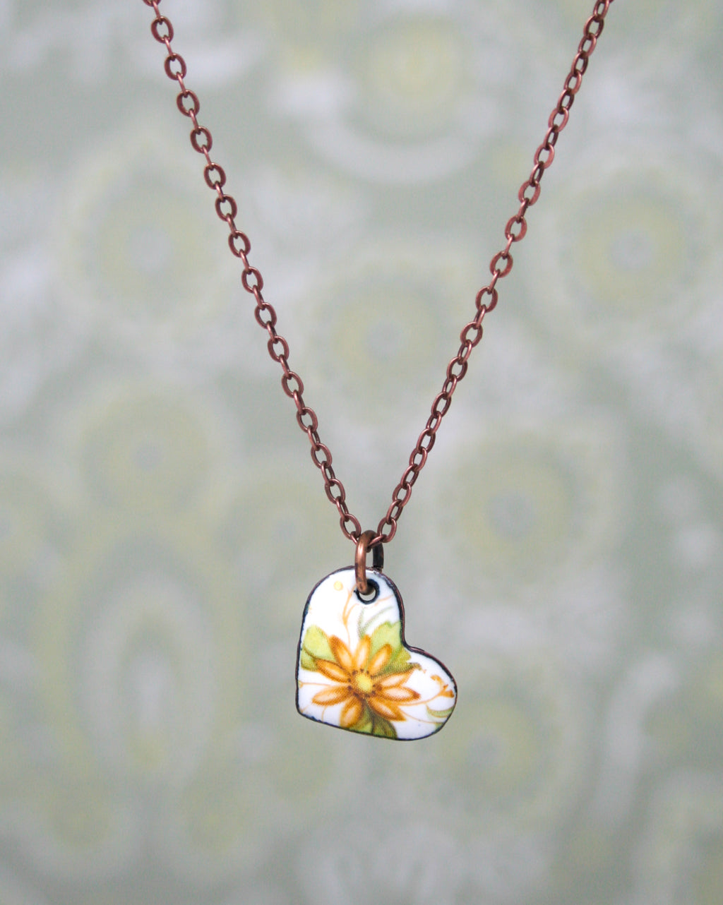 a heart shaped pendant with a flower painted on it