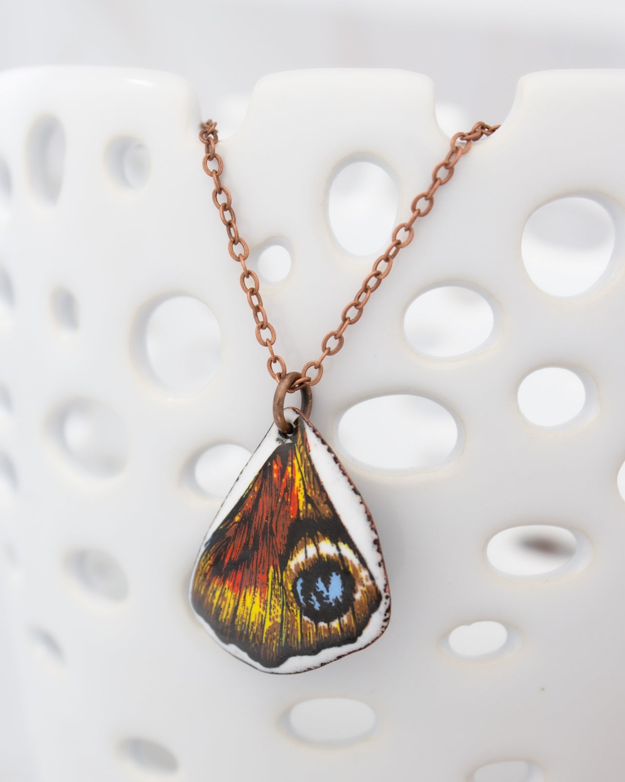 A necklace with a pendant featuring a colorful butterfly wing design.