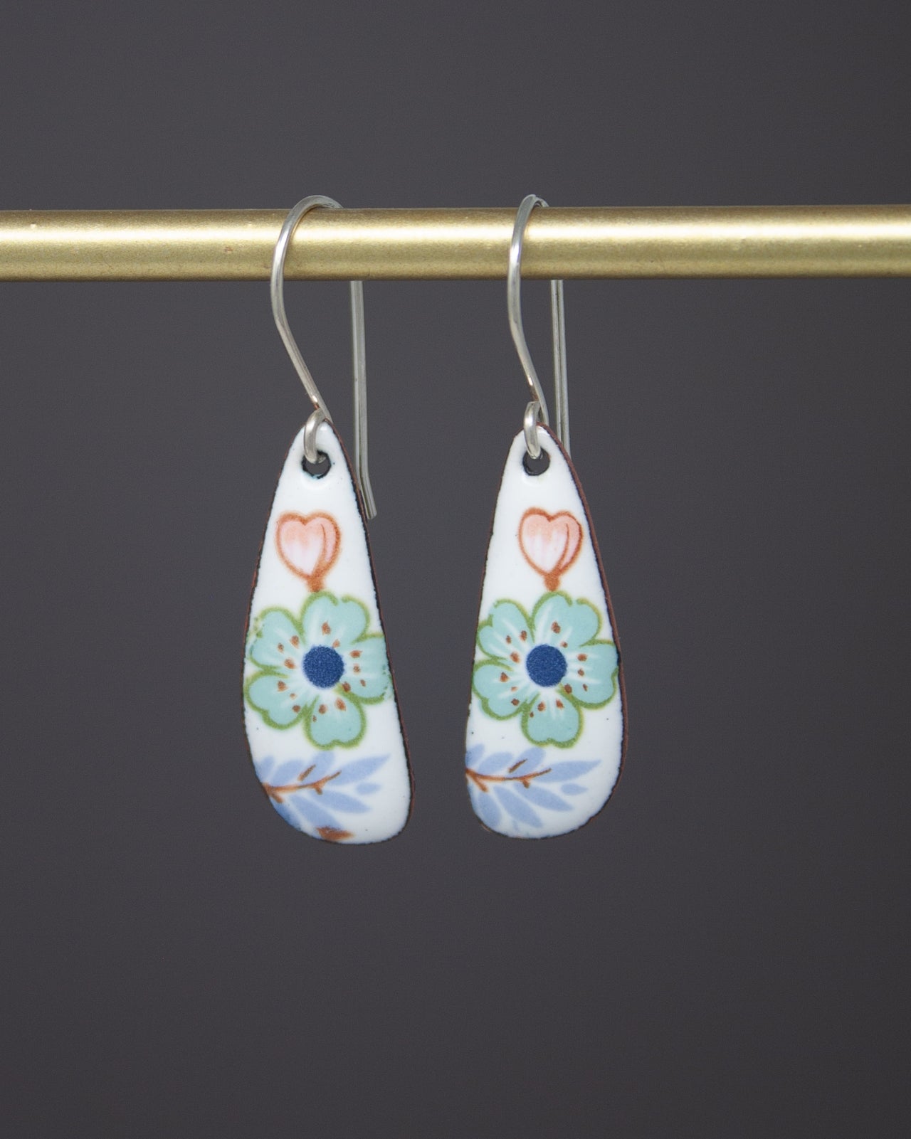 A pair of earrings with a floral design on a dark background.