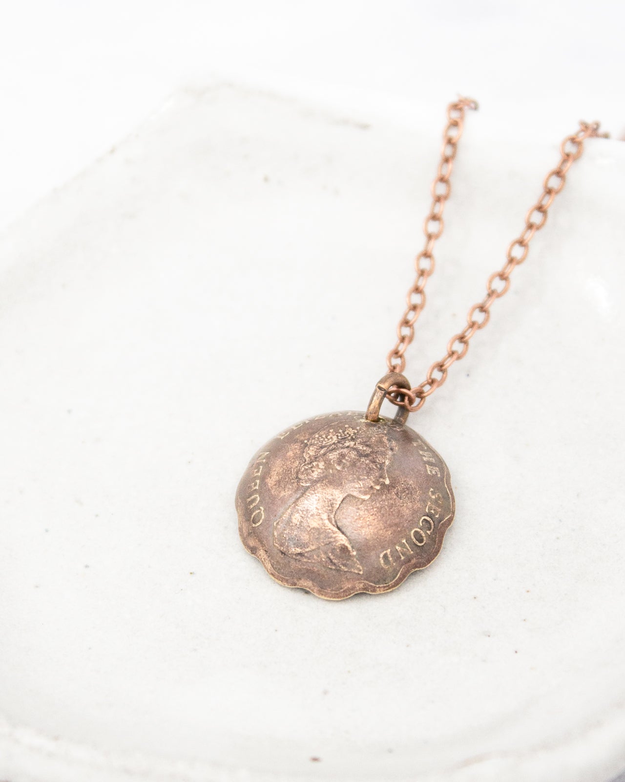 A necklace with a round metal pendant featuring a profile portrait of a person.