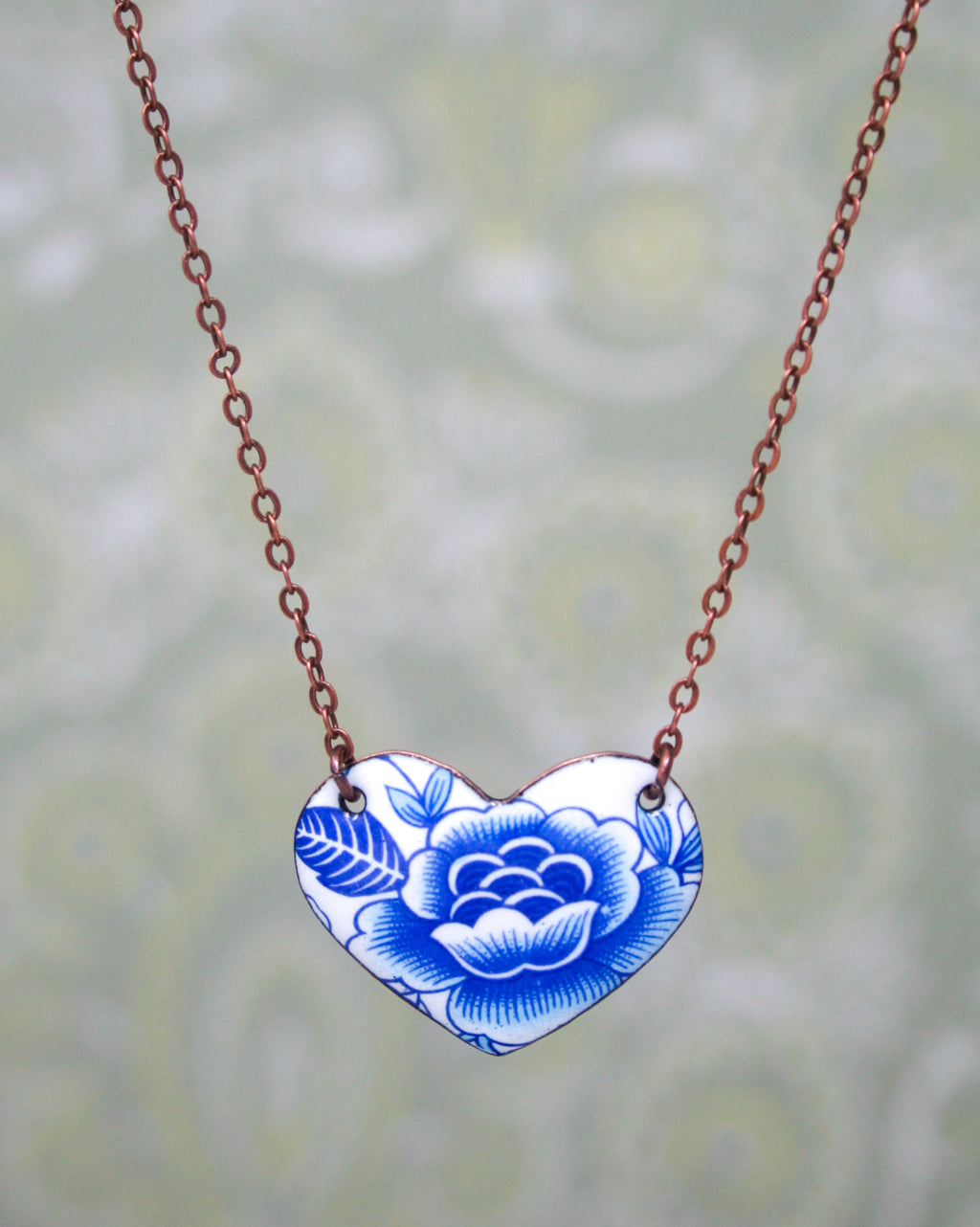 a blue and white heart shaped necklace on a chain