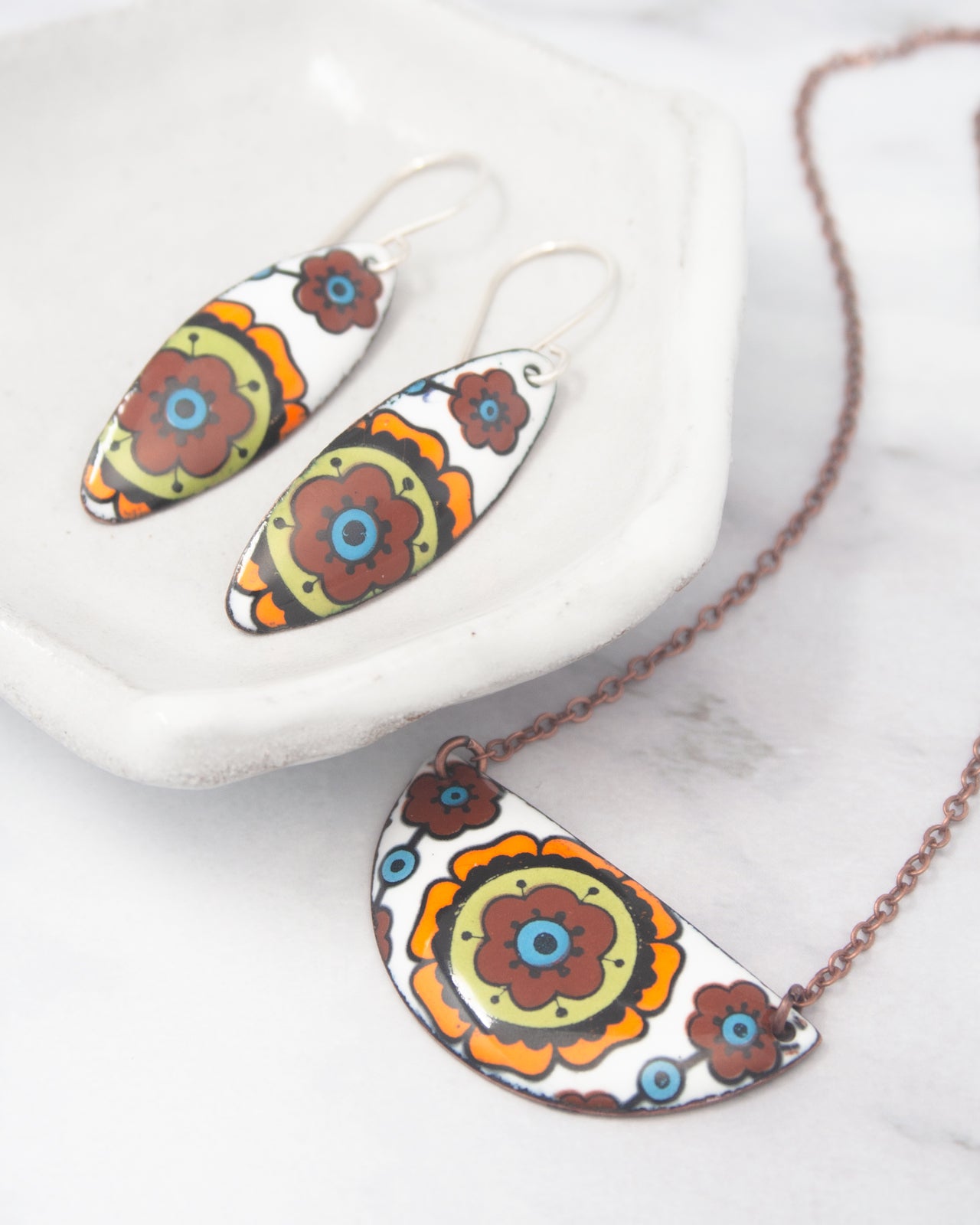 a pair of earrings and a necklace with colorful floral designs.