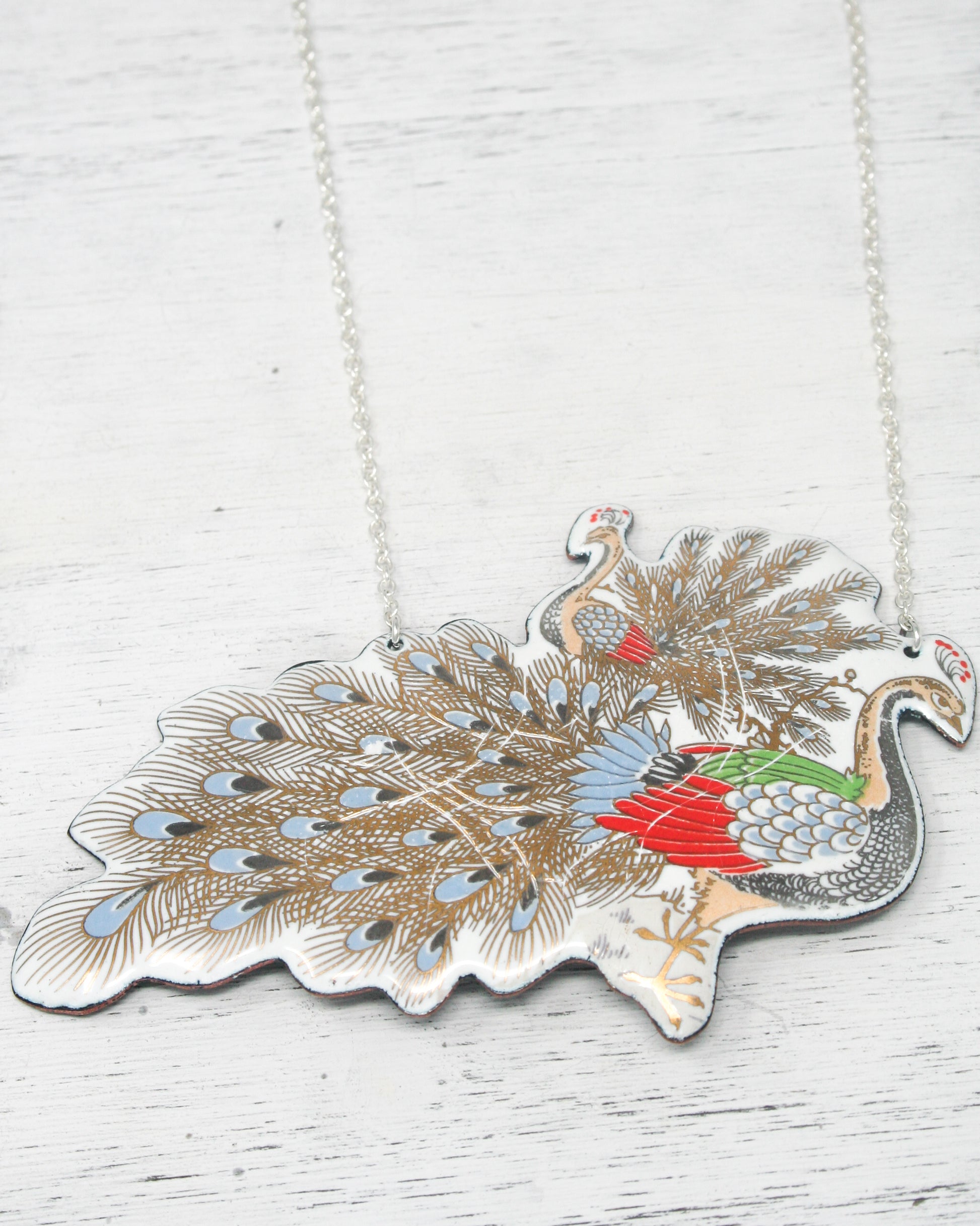 a silver necklace with a peacock on it