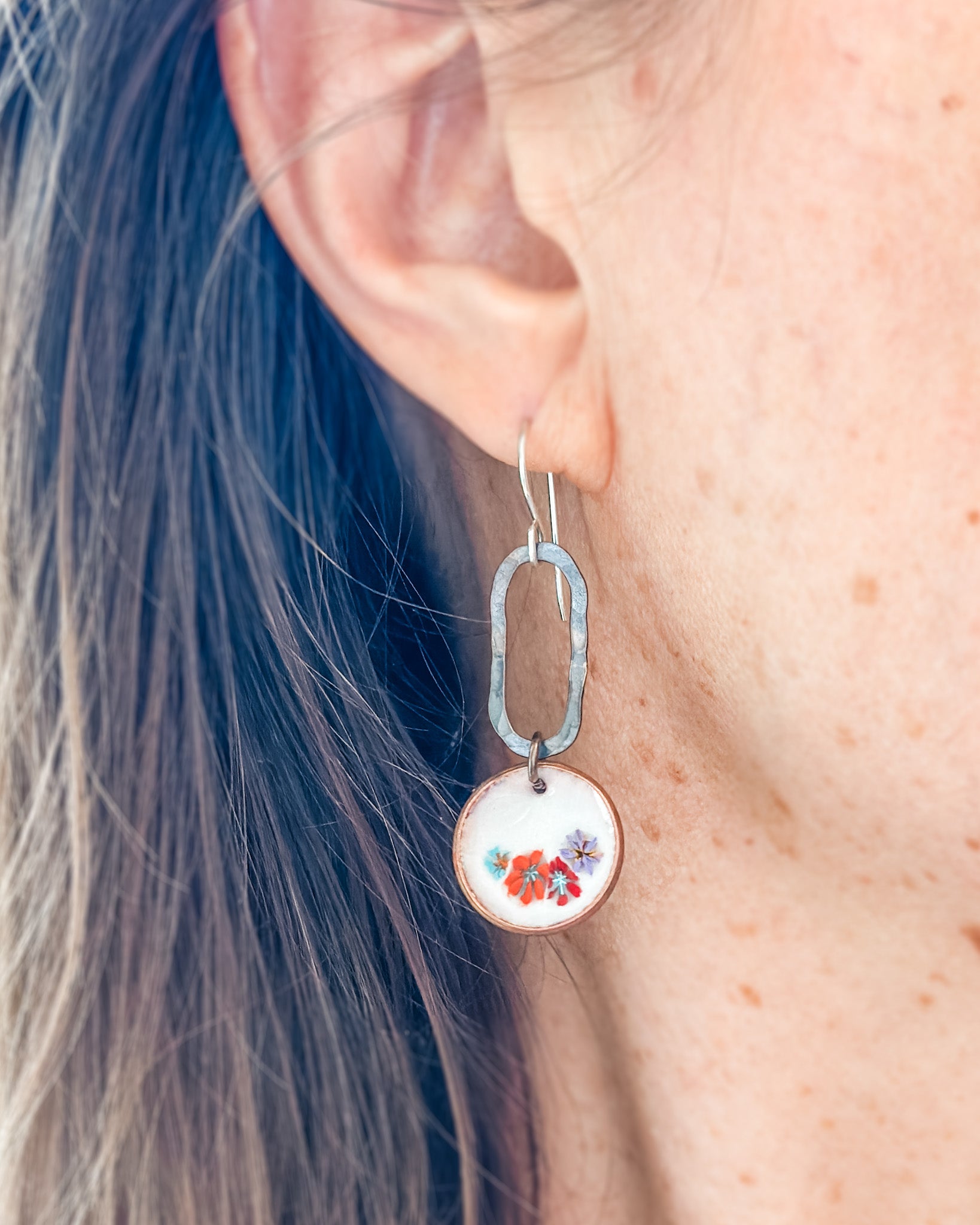 a close up of a person wearing a pair of earrings